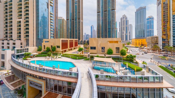 A modern high-rise building with a rooftop pool and landscaped areas. - EDEN'S Homes & Villas - Opera Grand (Dubai)