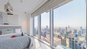 A modern bedroom with a large bed, a city view, and a cityscape visible through the window. - EDEN'S Homes & Villas - Opera Grand (Dubai)