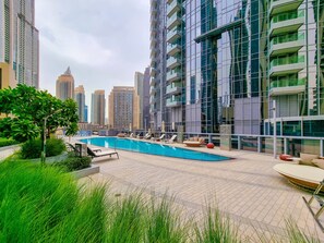 A rooftop pool area with lounge chairs and a view of surrounding high-rise buildings.