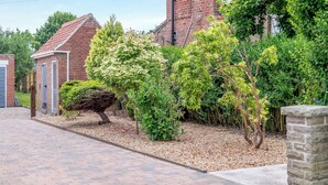 Een woonwijk met bakstenen huizen, een verharde oprit en verzorgde beplanting.