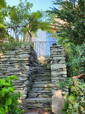 A stone staircase leading to a gated entrance, surrounded by lush greenery and a metal gate. - Lingmoor Cottage - Three Bedroom House, Sleeps 6 (Chapel Stile)