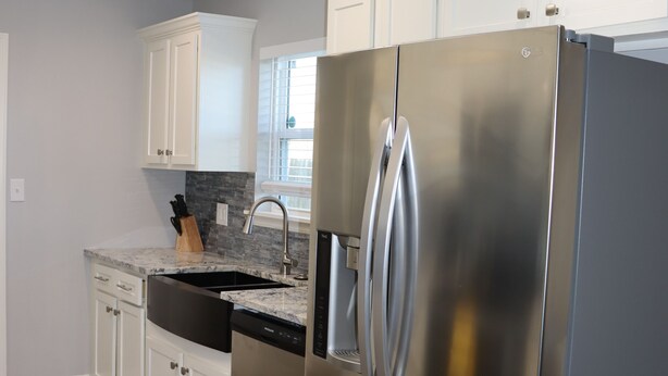 A modern kitchen with stainless steel appliances, white cabinetry, and a wooden floor. - Chisholm Creek by Top golf 3 (Oklahoma City)