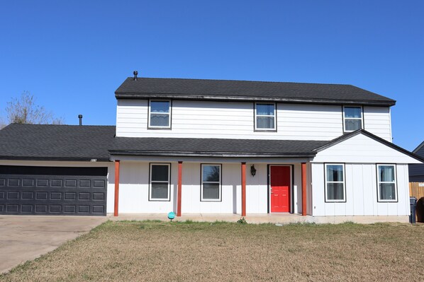 A two-story house with a red door, white siding, and a garage. - Chisholm Creek by Top golf 3 (Oklahoma City)