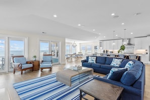Relax in the living area with a sofa, armchairs, and a coffee table, surrounded by a view of the outdoors.