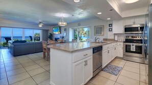 A modern kitchen with white cabinetry, a central island, stainless steel appliances, and a view to the outside.