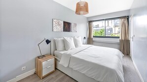 A bedroom with a bed, bedside table, lamp, and artwork on the wall. - Muette - Lamartine 1bdr by B'Your Home (Paris)