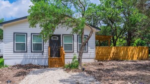 A single-story house with a front porch, a wooden fence, and a gravel driveway. - Levy inn Luxury cottage (San Antonio)