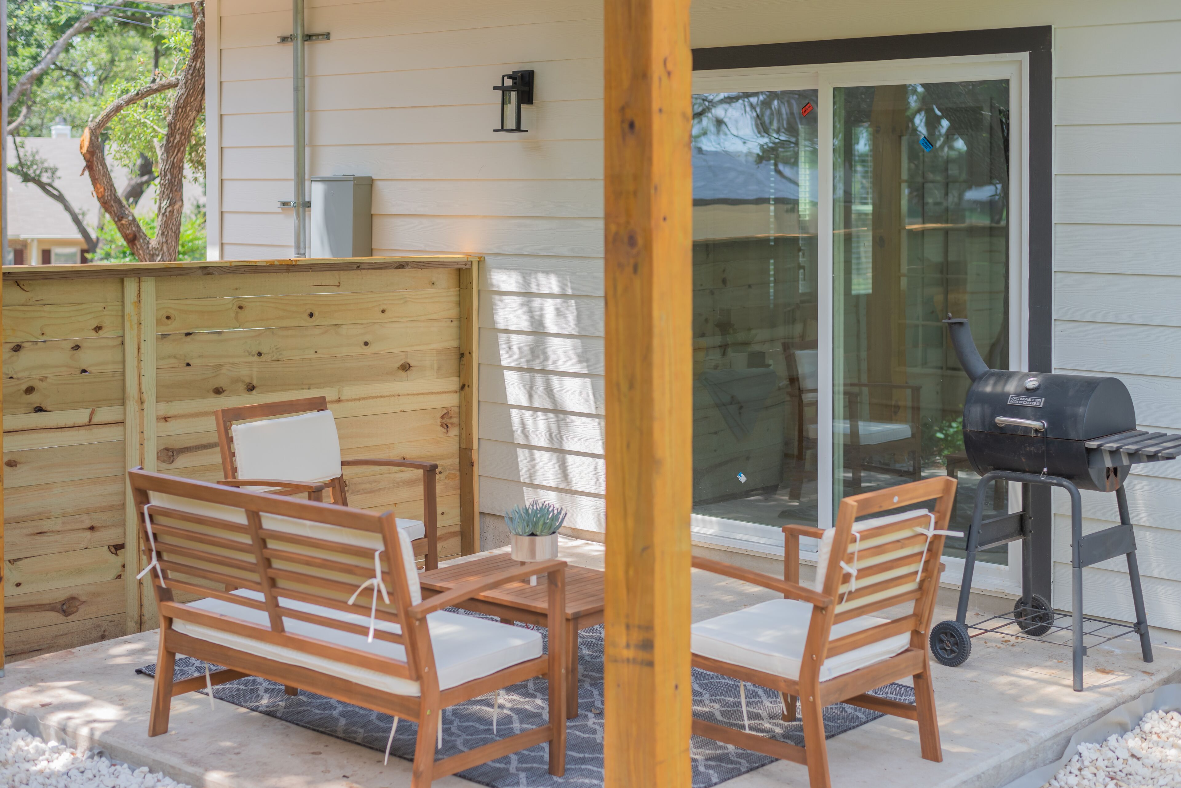 Un patio con mobili in legno e un barbecue.