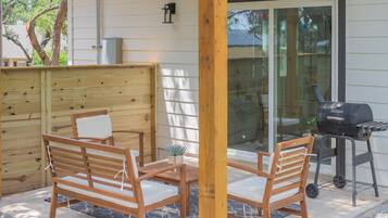 Un patio con mobili in legno e un barbecue.