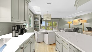 Een moderne keuken met witte kasten, een groot eiland en een eetgedeelte met een ronde tafel en stoelen.