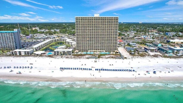 Un hotel frente a la playa con varias construcciones, una playa de arena y una vista despejada del océano.
