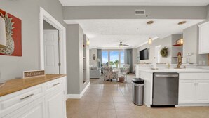Una cocina amplia con muebles blancos, una isla central y un lavavajillas.