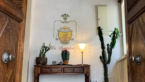Una consola de madera con una planta en maceta, una lámpara y un emblema enmarcado en la pared.
