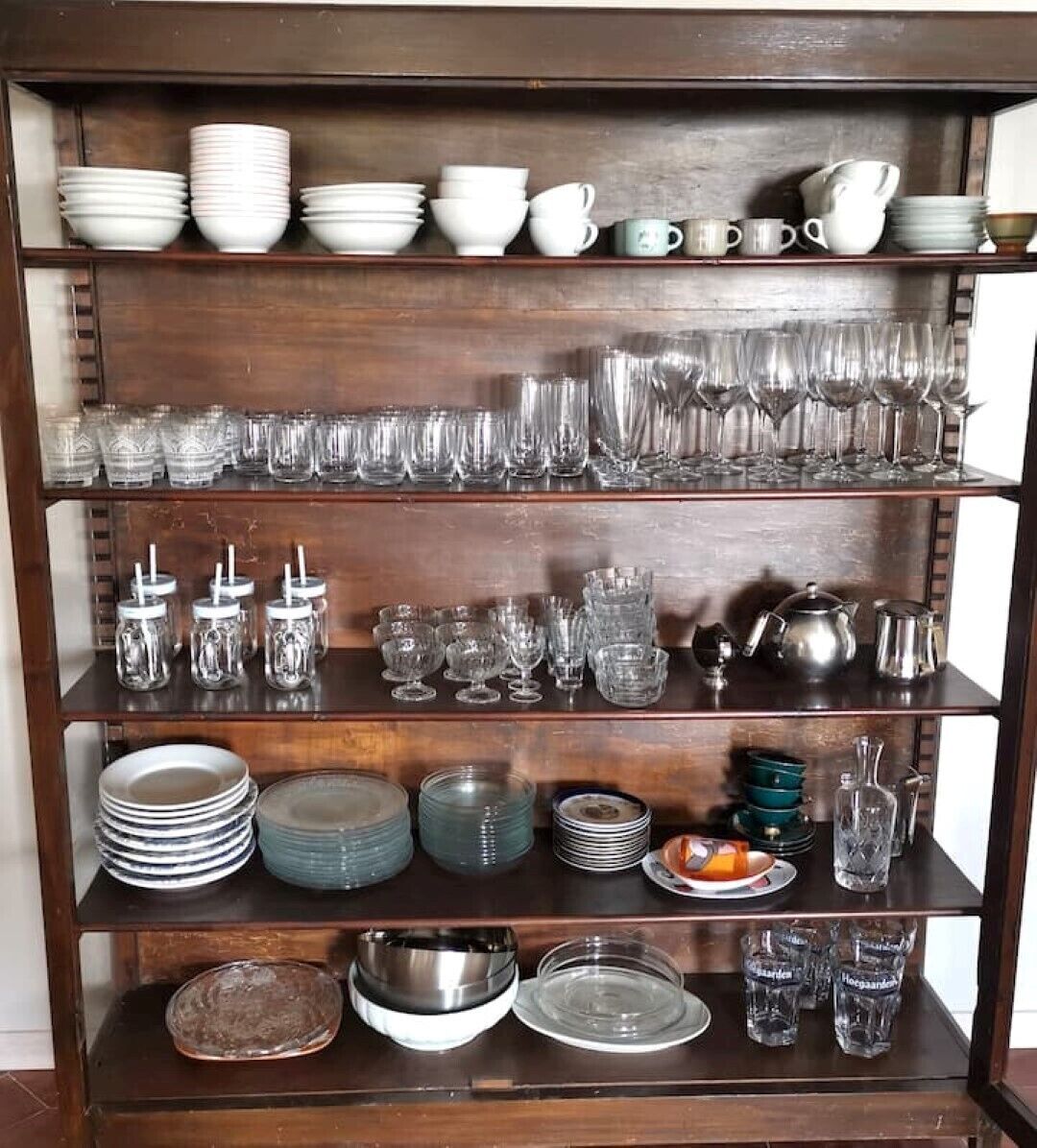Una estantería de madera con diferentes vasos y platos.