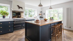 Una cocina moderna con una isla grande, armarios oscuros y piso de madera.