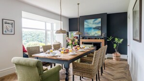 Un comedor con una mesa de madera, sillas de mimbre y vistas a la vegetación exterior.