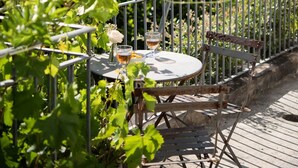 Una terraza con una mesa y sillas, con vistas a un viñedo y colinas.