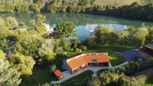 Une propriété située au bord d’un lac, comprenant une maison principale, un bâtiment plus petit et un quai pour bateaux.