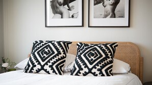A bed with two patterned pillows, a white bedspread, and a framed picture above the bed. - Murrawingi -  a beautiful modern coastal home (Salcombe)