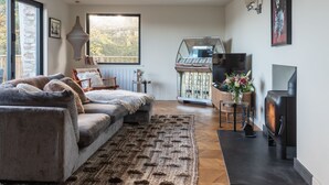 A cozy living room with a sofa, a fireplace, and a TV. - Murrawingi -  a beautiful modern coastal home (Salcombe)