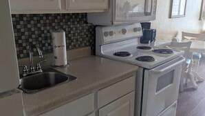 Una cocina con armarios blancos, microondas, estufa y salpicadero de azulejos.