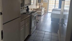 Una cocina con armarios blancos, un refrigerador, una estufa y un lavamanos.