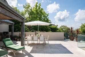 Eine Terrasse mit Esstisch, Stühlen und einem grünen Liegestuhl.