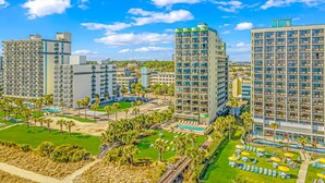 Un hôtel de grande hauteur doté de nombreux balcons, d’un espace piscine et d’une pelouse bien entretenue.