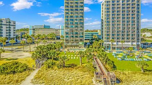 Un hôtel comprenant plusieurs étages, un espace piscine et un chemin d’accès à la plage.