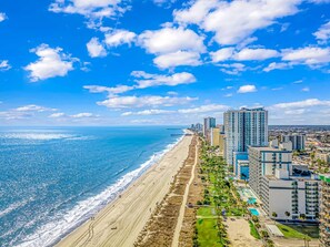 Un paisaje urbano costero con playa, edificios altos y cielos despejados.