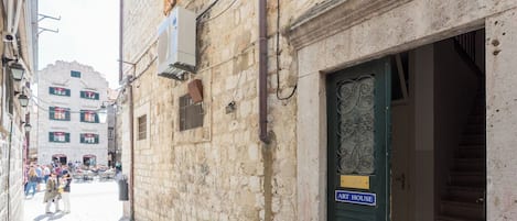 A narrow street with a building labeled "ART HOUSE" and a sign indicating a central location without outdoor stairs.