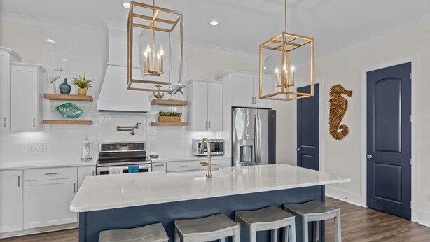 Cocina moderna con armarios blancos, una isla grande con taburetes de bar, electrodomésticos de acero inoxidable y decoración en la pared.