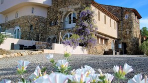 A stone building with arched windows and a balcony, surrounded by gravel and flowering plants. - Luxe Appartement met 2 Slaapkamers, Groot Terras Direct aan Zwembad La Mourre 16 (Le Plan-de-la-Tour)