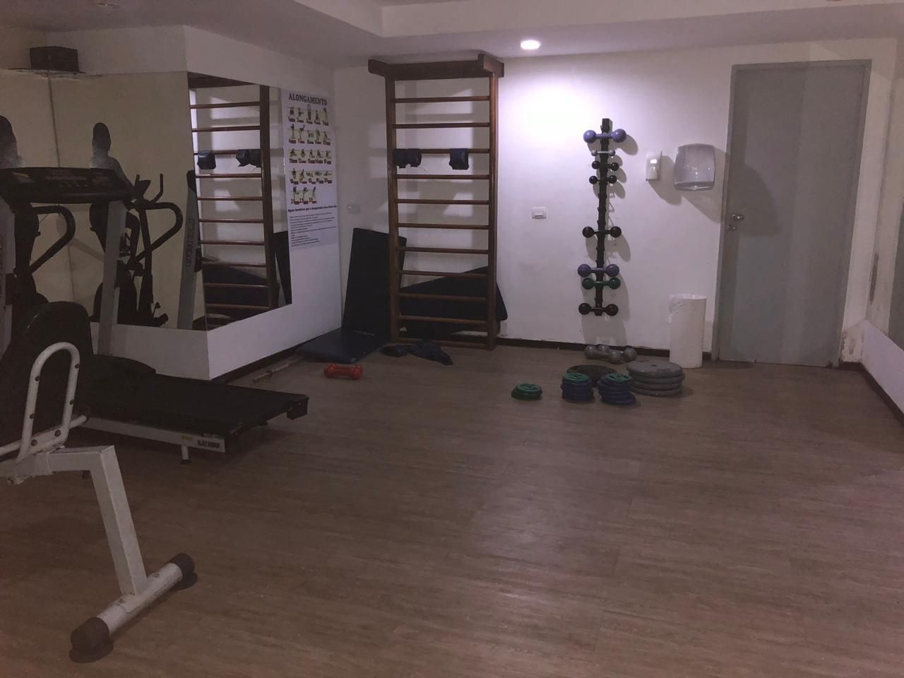 A gym with exercise equipment, a pull-up bar, and weight plates.