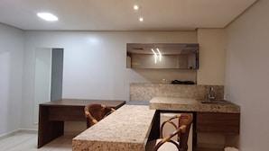 A modern bathroom with a large mirror, a sink, and a vanity. There is a wooden table and two wicker chairs. - Imperial Suítes (João Pessoa)