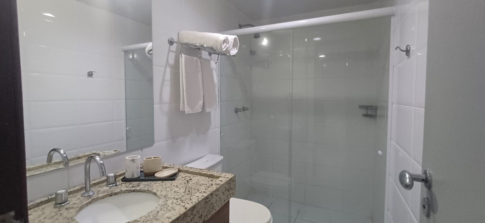 A modern bathroom with a glass shower enclosure, a sink with a marble countertop, and a toilet.