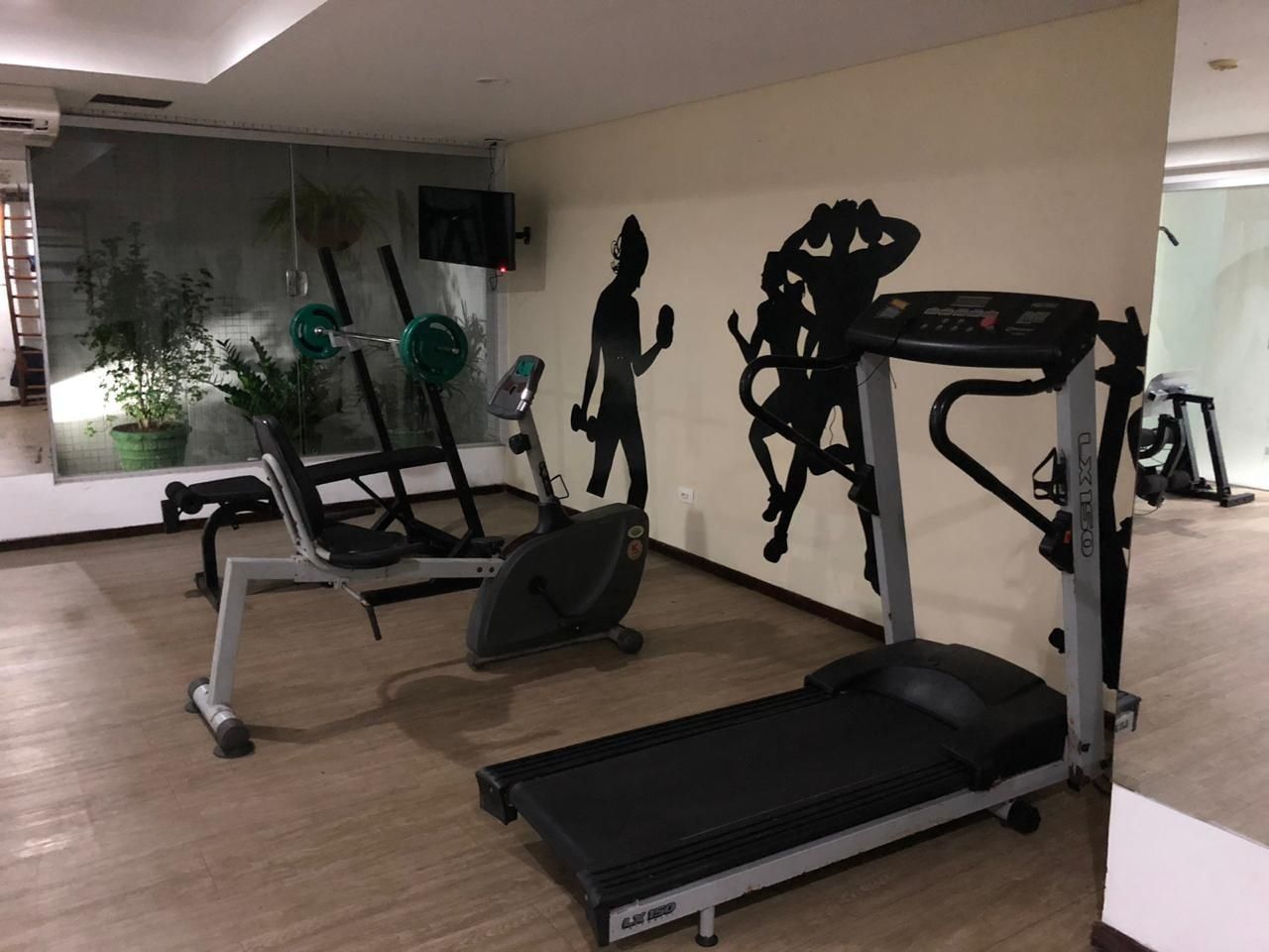 A gym with cardio equipment, weight machines, and a mirror.