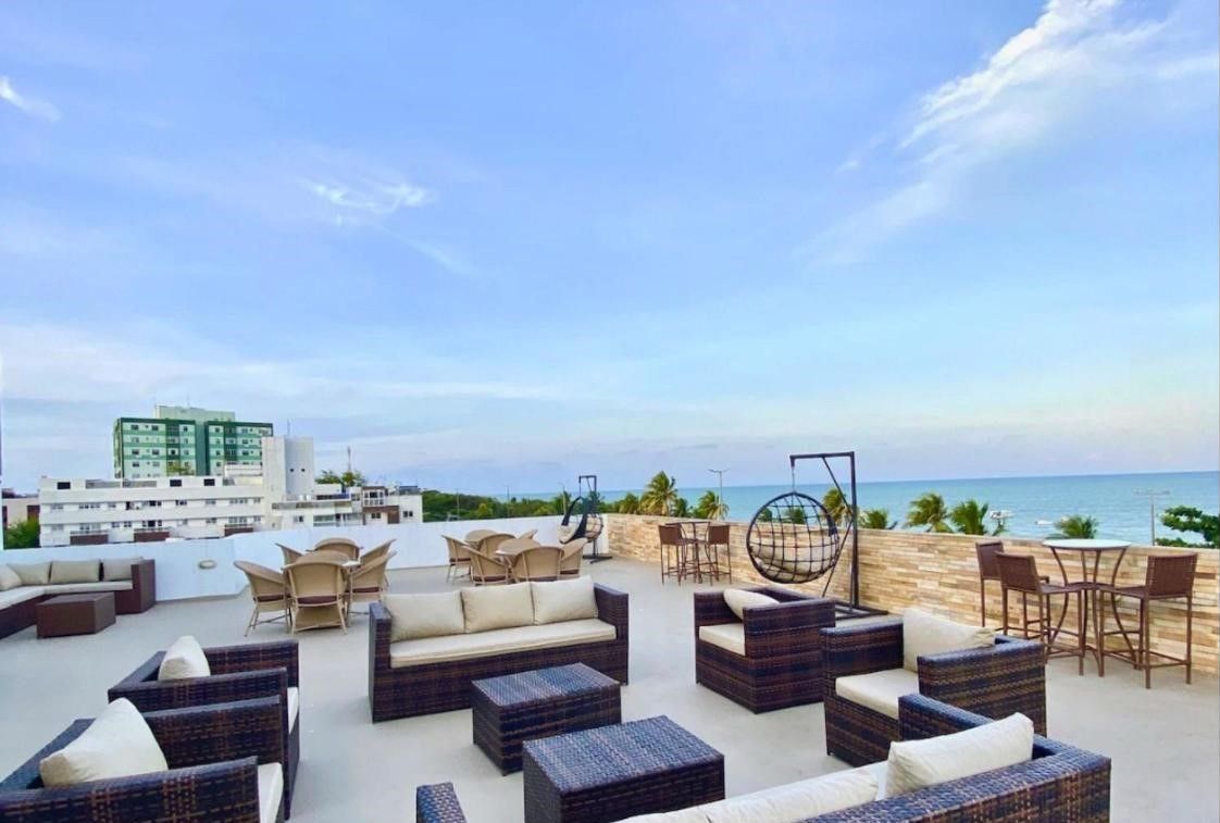 A rooftop terrace with outdoor seating, a swing chair, and a view of the ocean.