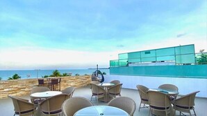 A terrace with wicker furniture and a view of the sea. - Imperial Suítes (João Pessoa)