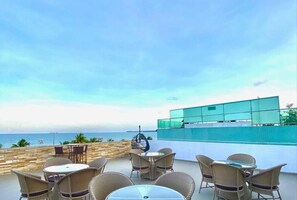 A terrace with wicker furniture and a view of the sea. - Imperial Suítes (João Pessoa)