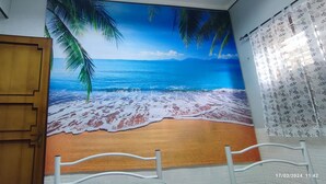 A room with a beach mural, a wooden door, and a white railing.