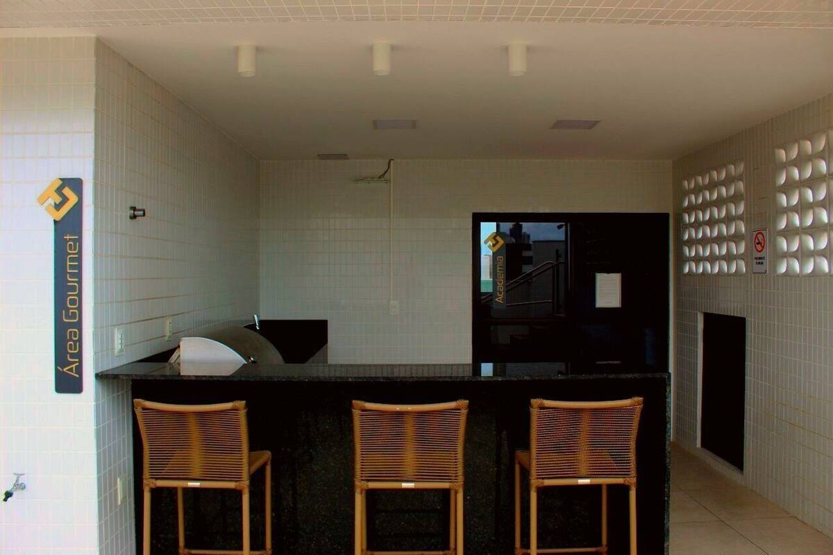 A modern kitchen with a black countertop, three wicker chairs, and a sign reading "Area Gourmet".