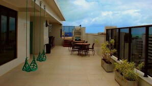A rooftop terrace with a dining area, hanging chairs, and potted plants. - Compact Flat Tambau (João Pessoa)