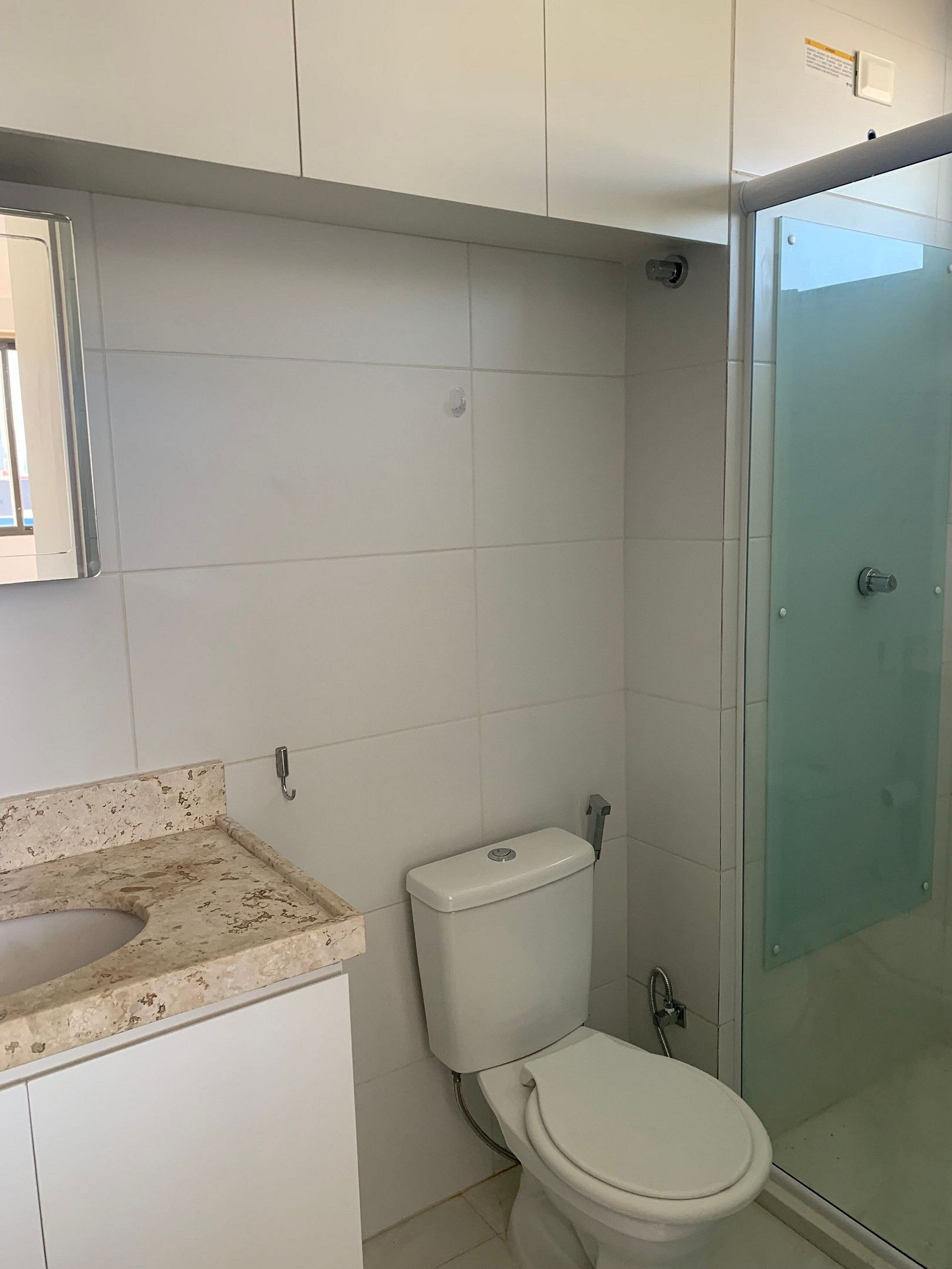 A bathroom with a toilet, a glass shower enclosure, and a sink with a speckled countertop.