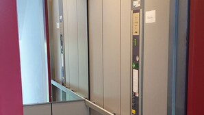 An elevator interior with a handrail, control panel, and emergency instructions. - Ferienwohnung Zentrale Lage (Idar-Oberstein)
