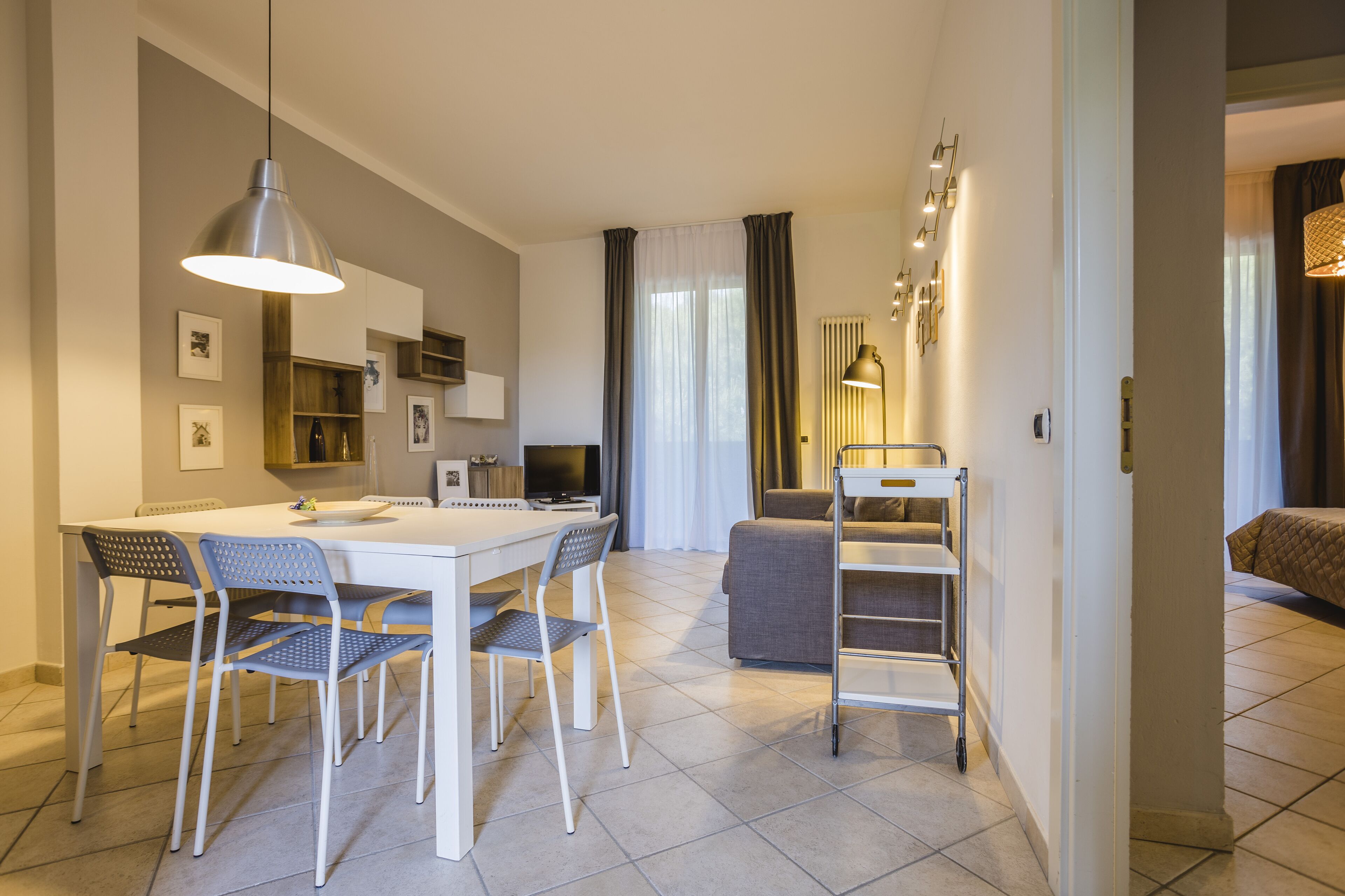 A modern living room with a sofa, a dining table with chairs, and a TV.