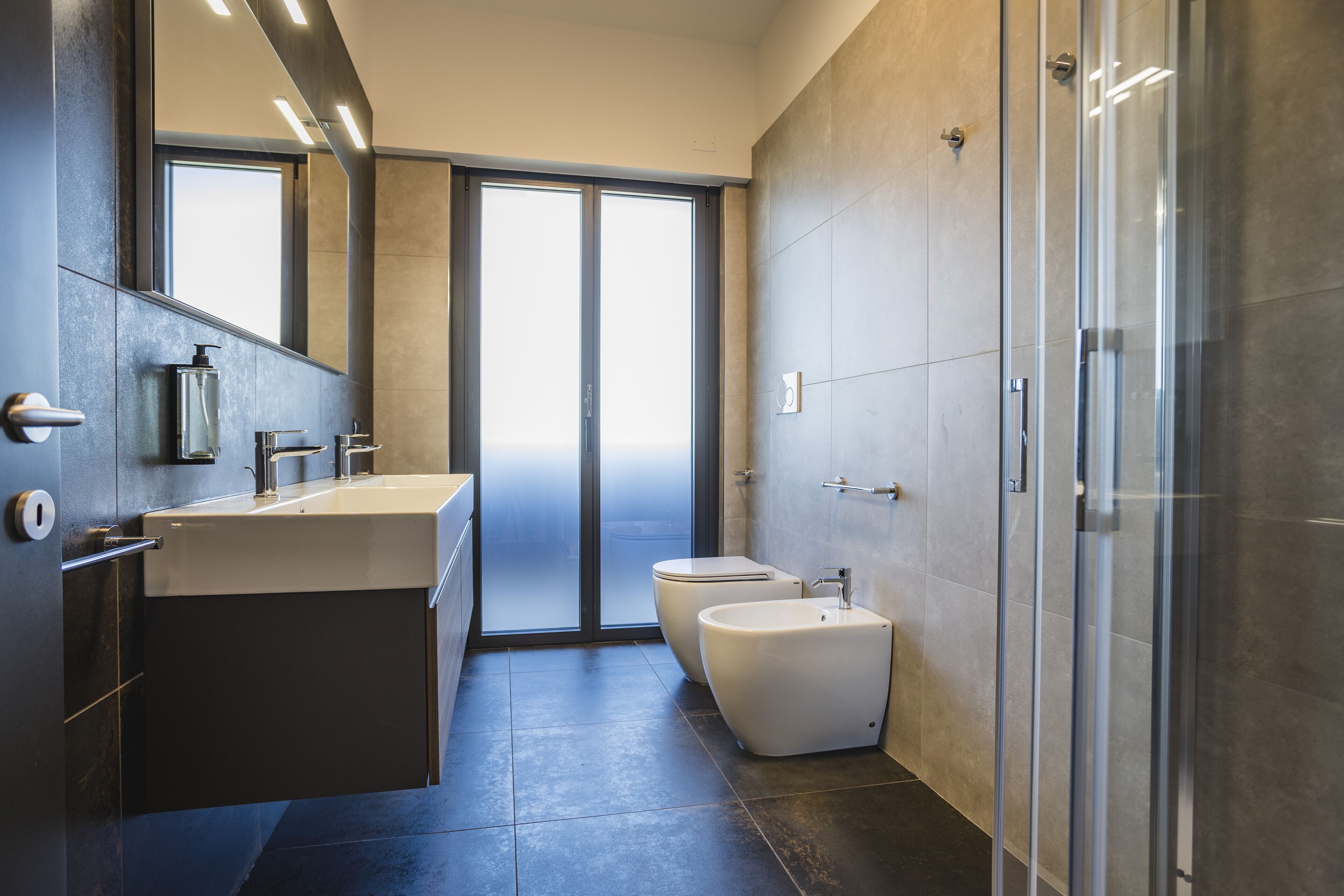 Een moderne badkamer met een grote spiegel, een wastafel, een toilet en een douchecabine.