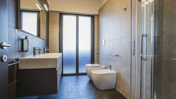 Een moderne badkamer met een grote spiegel, een wastafel, een toilet en een douchecabine.