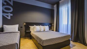 A hotel room with a large bed, a smaller bed, and a nightstand.