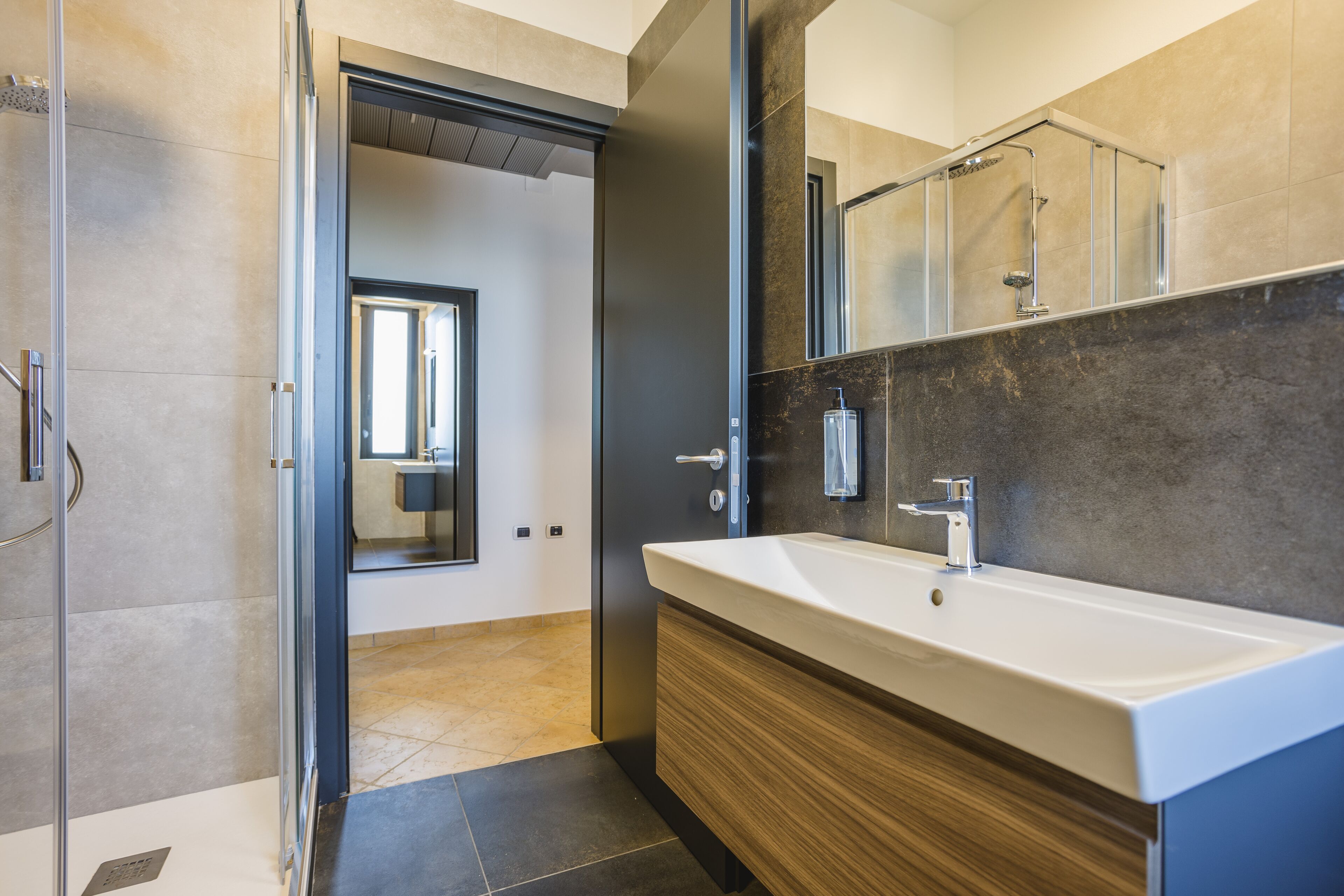 Un bagno moderno con un lavandino ampio, uno specchio e una zona doccia.